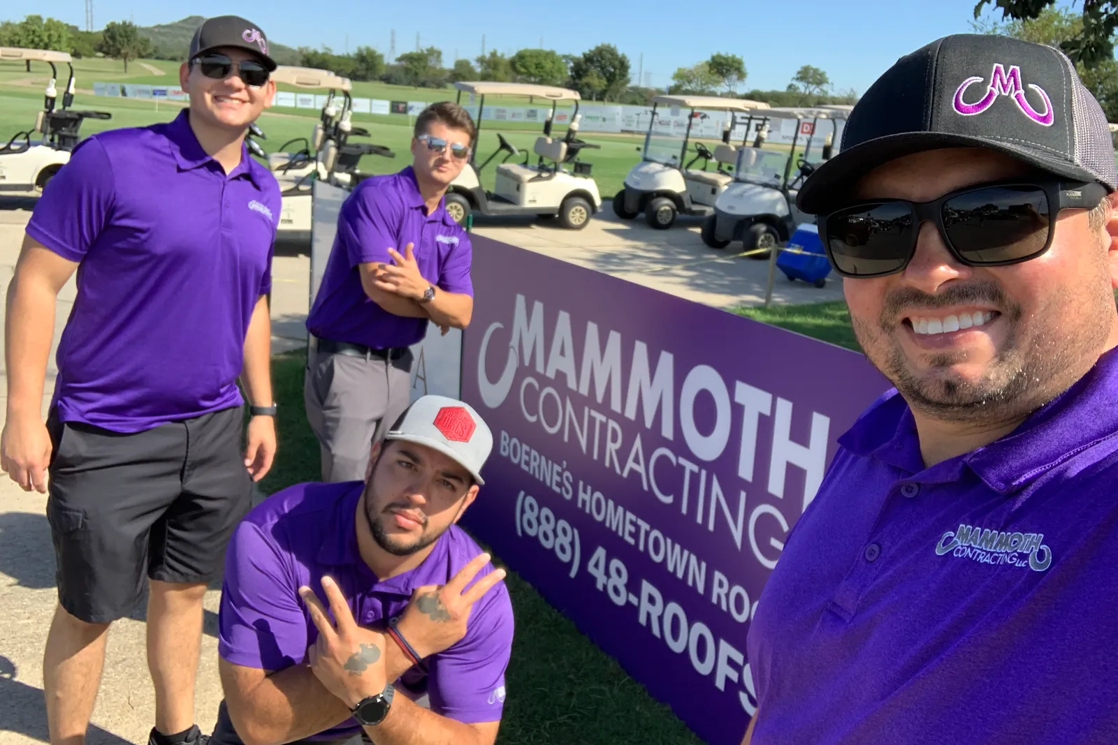 Four Mammoth team members in purple shirts beside a Mammoth Contracting banner at a golf tournament