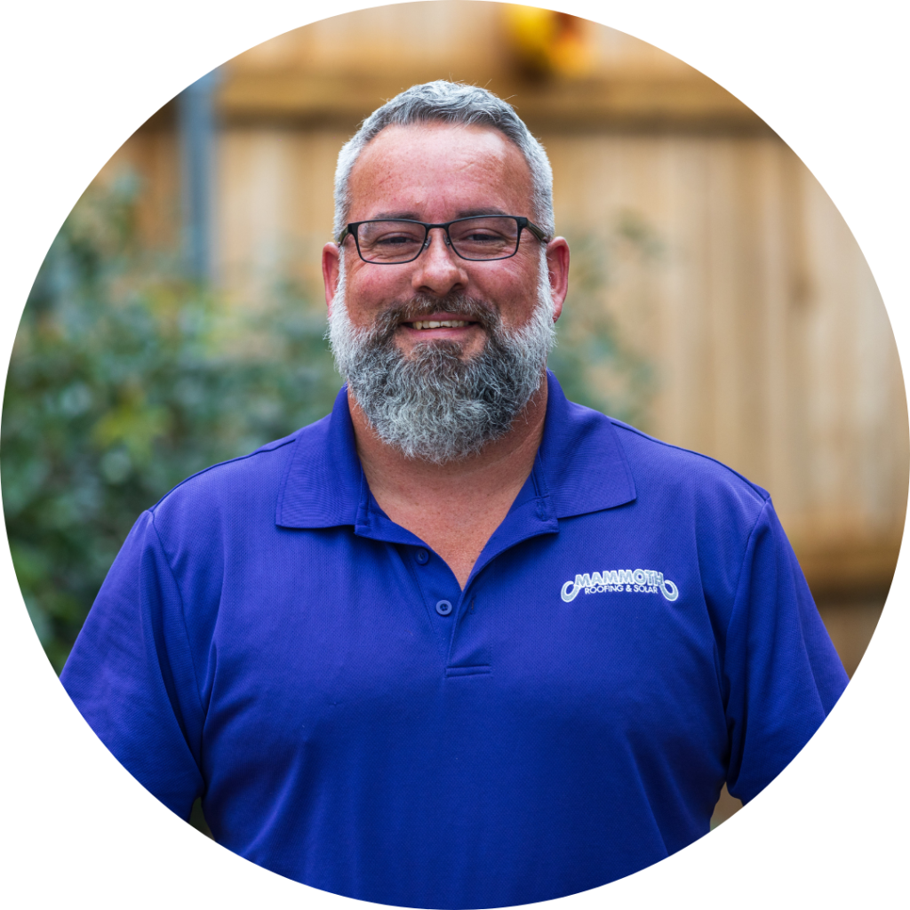 Sean McGuire - Roofing Specialist at Mammoth Roofing & Solar, wearing a purple polo and glasses, smiling in an outdoor setting.
