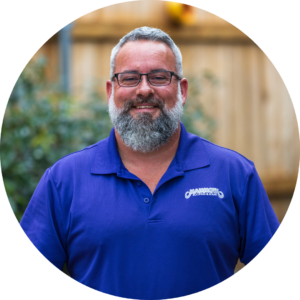 Sean McGuire - Roofing Specialist at Mammoth Roofing & Solar, wearing a purple polo and glasses, smiling in an outdoor setting.