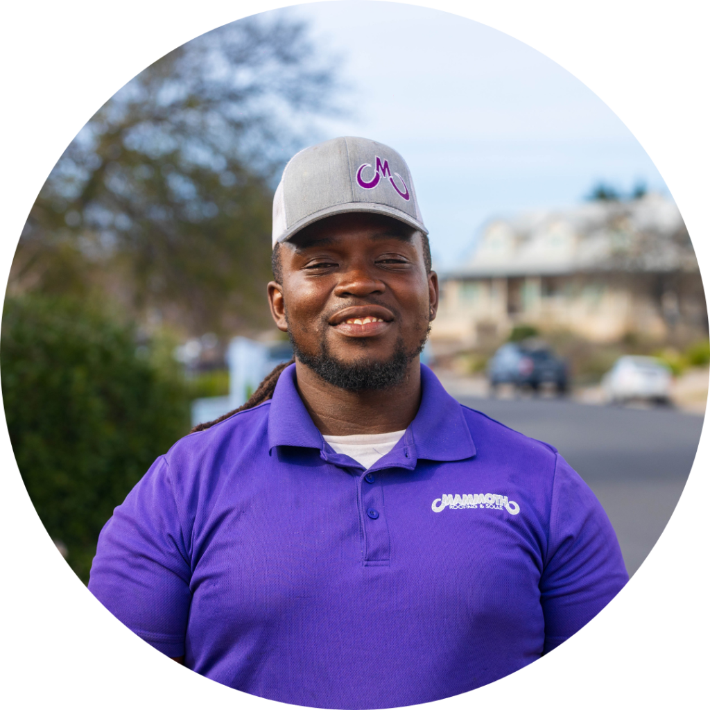 Jaheem Jeffers, Mammoth Roofing & Solar team member wearing branded uniform and hat, smiling on a residential street.